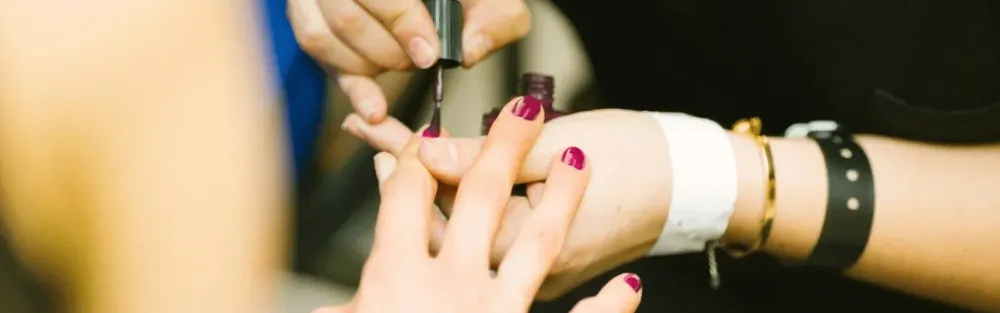 Manicure pintando a unha de uma cliente.